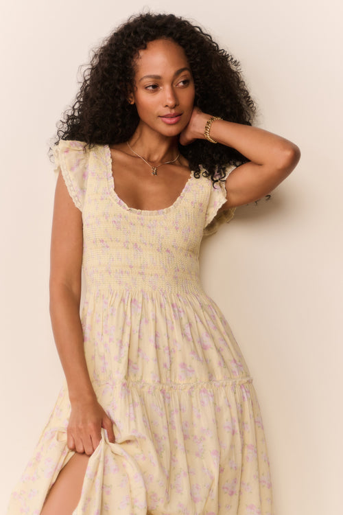 Woman wearing a yellow floral dress against a beige background