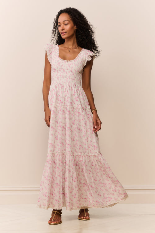 Woman wearing a maxi floral dress against a plain background