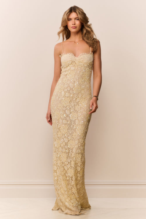 Woman wearing a long, floral lace dress against a plain background