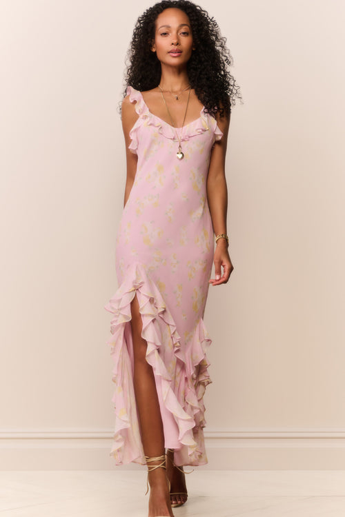 Woman wearing a pink floral ruffled dress against a white background