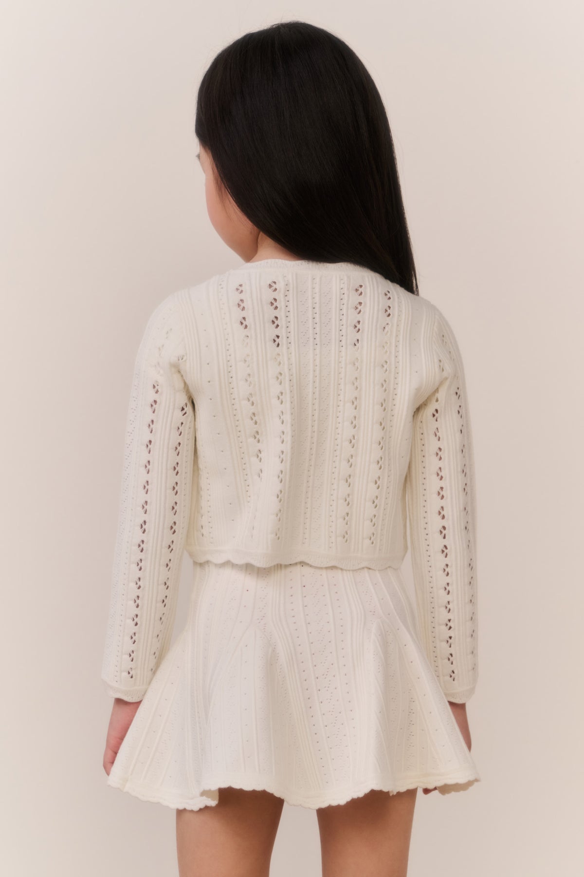 Girls cream pointelle knit cardigan, back view with textured vertical stripe pattern