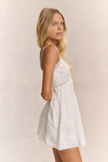 White cotton mini dress side view with spaghetti straps and lace-trim tiered skirt