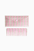 Pink and green floral hair comb with fine teeth, shown with backing card