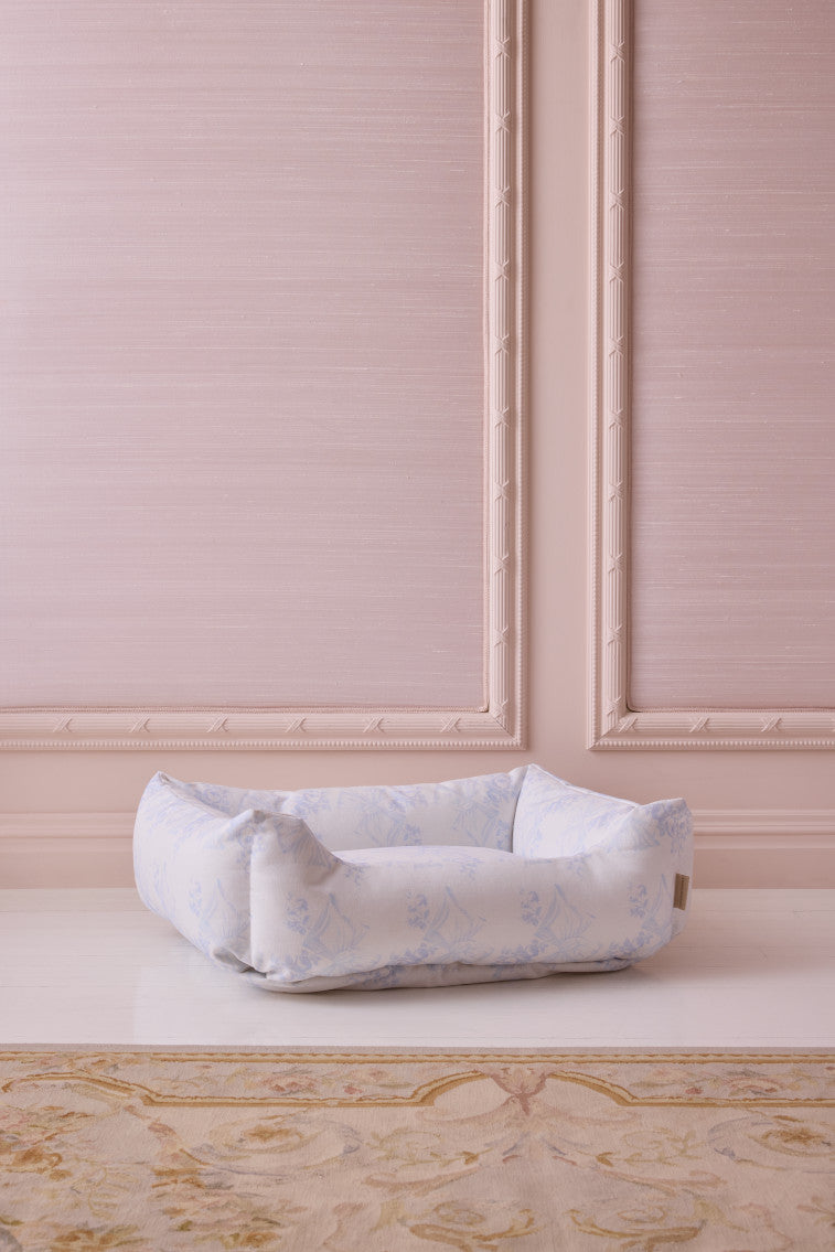 Printed dog bed with pale blue floral fabric and rolled bolstered sides
