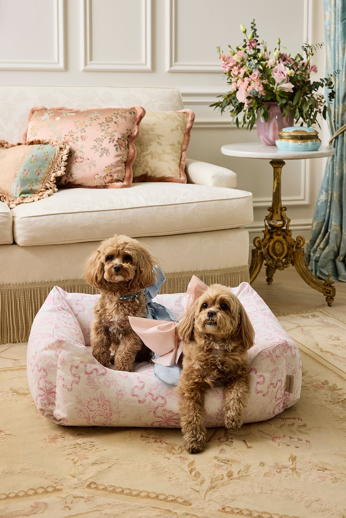 Printed dog bed with pink floral cover and two small dogs sitting in it