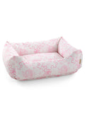Printed dog bed with light pink floral fabric and rounded bolstered sides