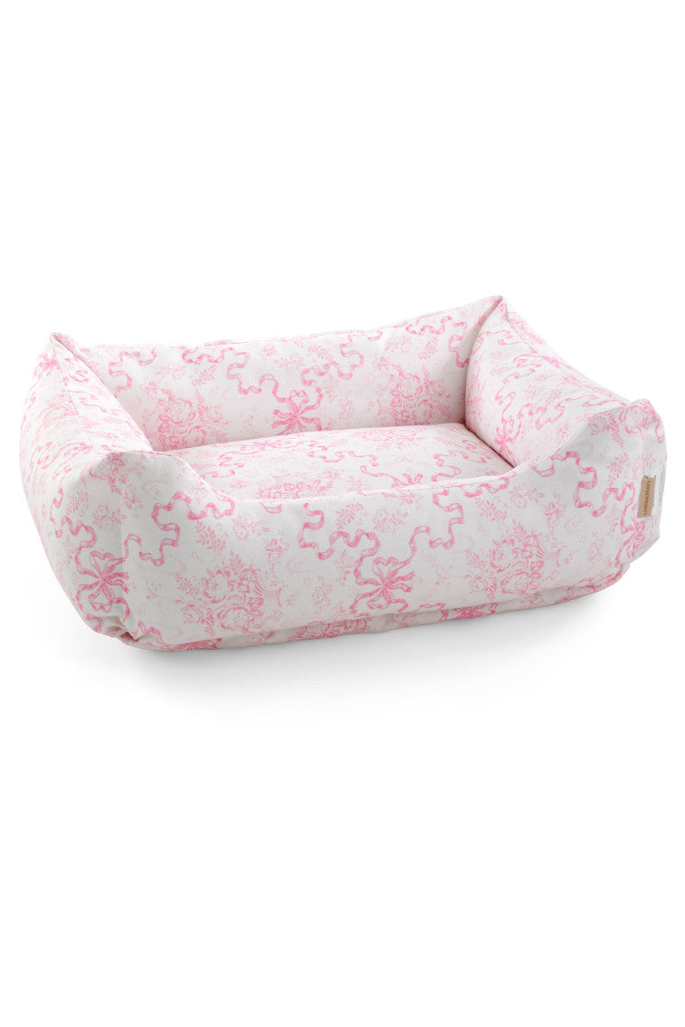 Printed dog bed with light pink floral fabric and rounded bolstered sides
