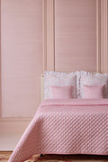Pink diamond-quilted quilt with matching shams and ruffled edge