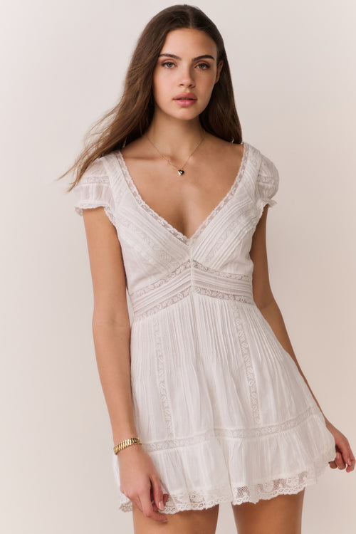 White cotton mini dress with puff sleeves, embroidered bodice, lace-trimmed tiered skirt