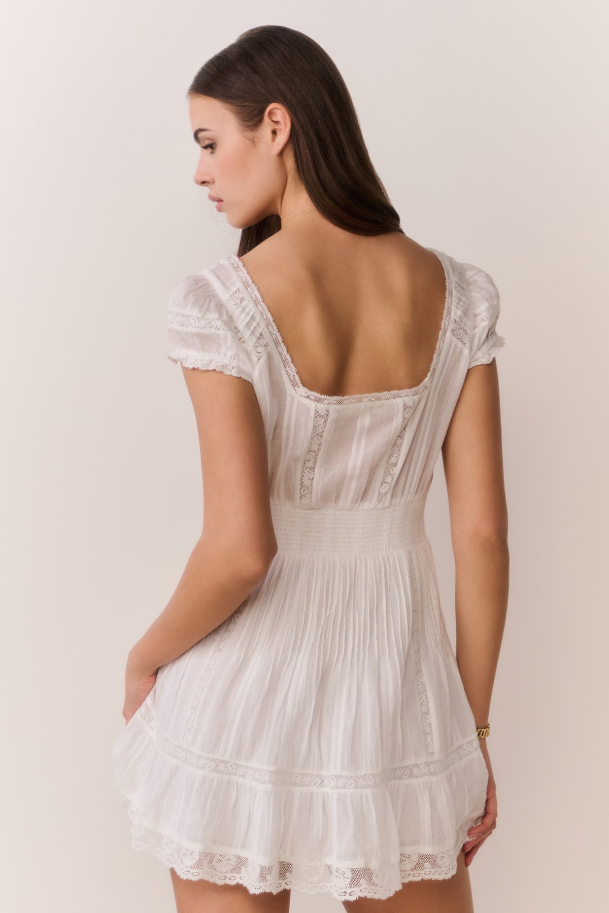 White cotton mini dress back view, cap sleeves with lace trim and tiered ruffles