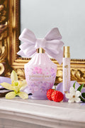 LoveShackFancy travel spray with purple pouch and white bow beside strawberries