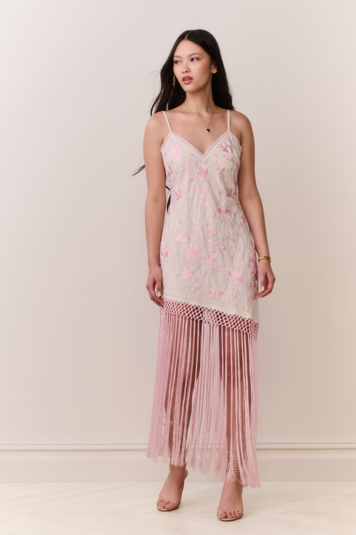 Pink floral maxi slip dress with spaghetti straps and long fringe along hem.