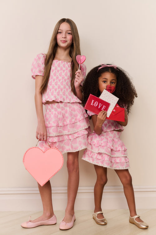 Tween pink heart-print peplum top with short puff sleeves and layered ruffles