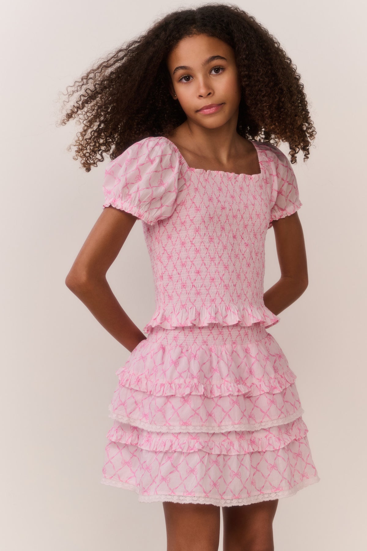 Pink short-sleeve top with square neckline, lattice print, and layered ruffle skirt