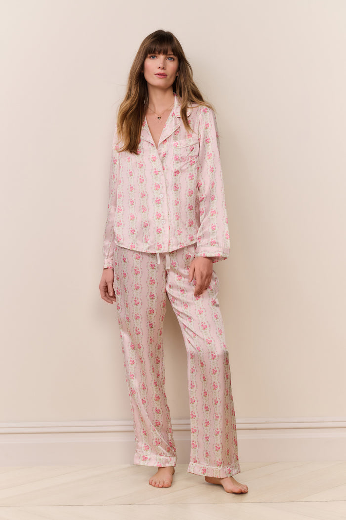 Woman wearing a pink floral pajama set against a plain background