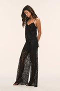 Black sheer lace wide-leg pants with lace paneling and bow at the waist.