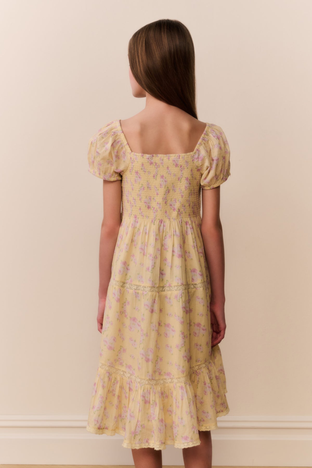 Yellow floral tiered dress from back view with square neckline and puff sleeves