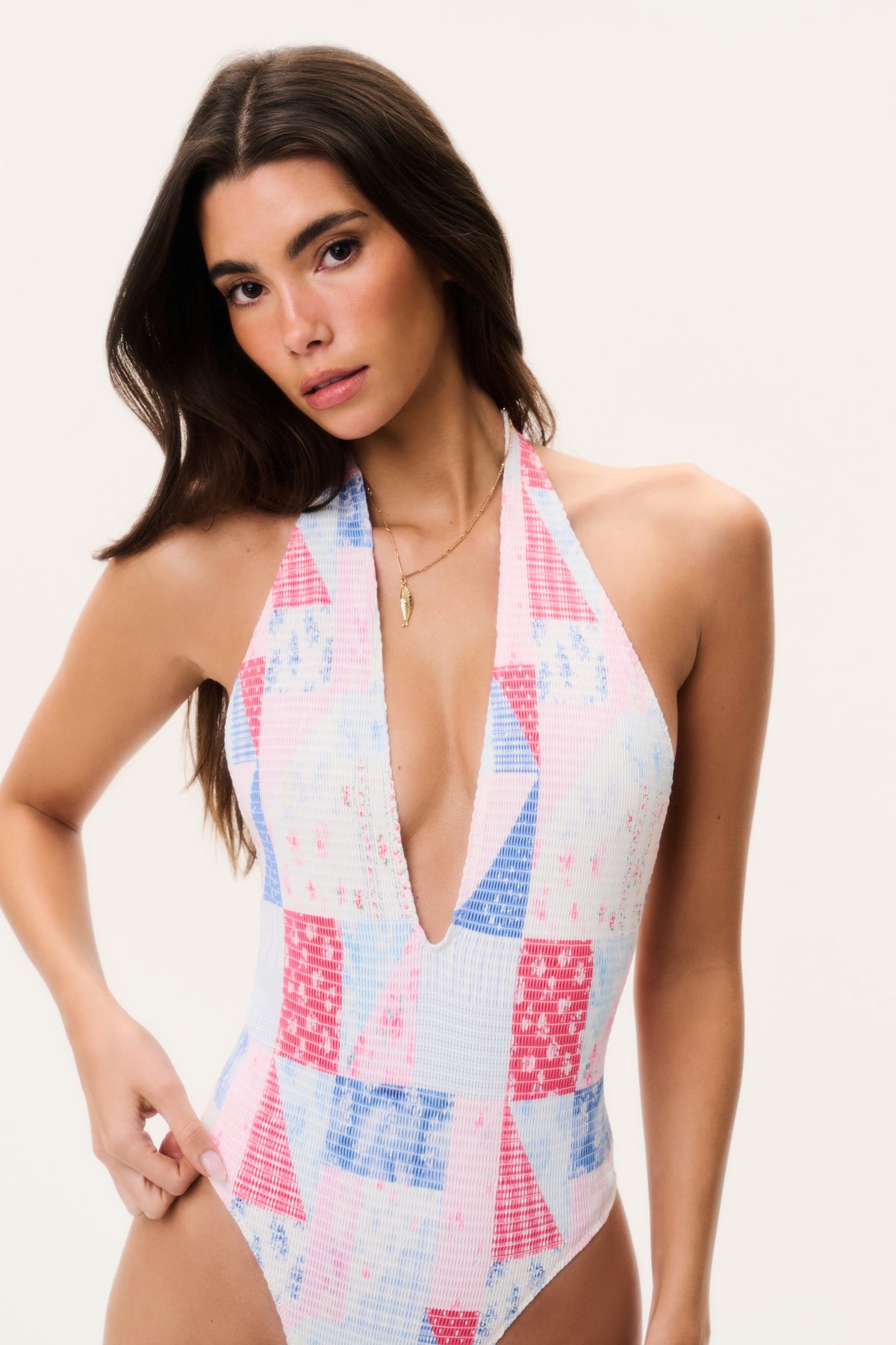 Halter one-piece swimsuit with plunging V-neck, patchwork print in white, blue, and pink.