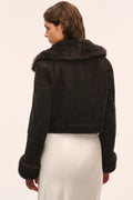 Back view of dark cropped shearling jacket with plush collar and fur-trim sleeves