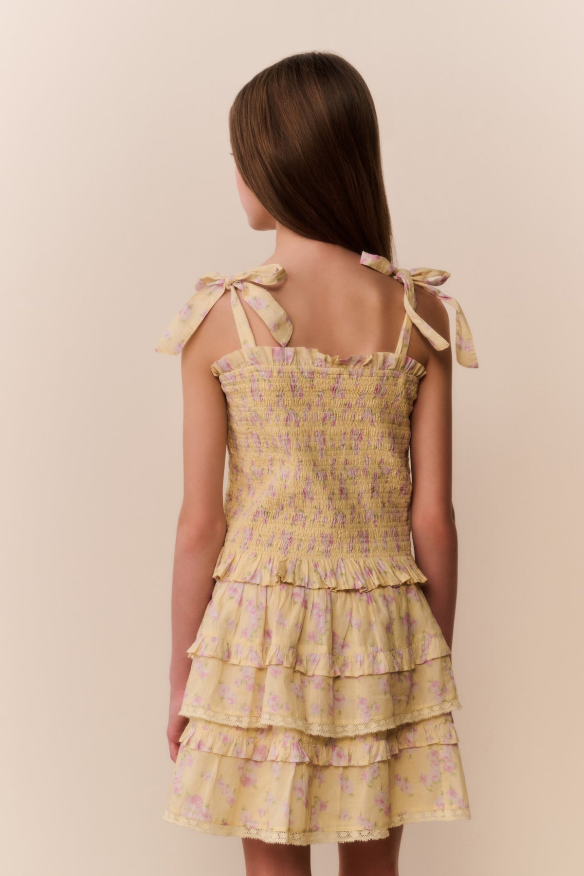 Tween floral top, back view, bow tie shoulder straps with tiered ruffle hem