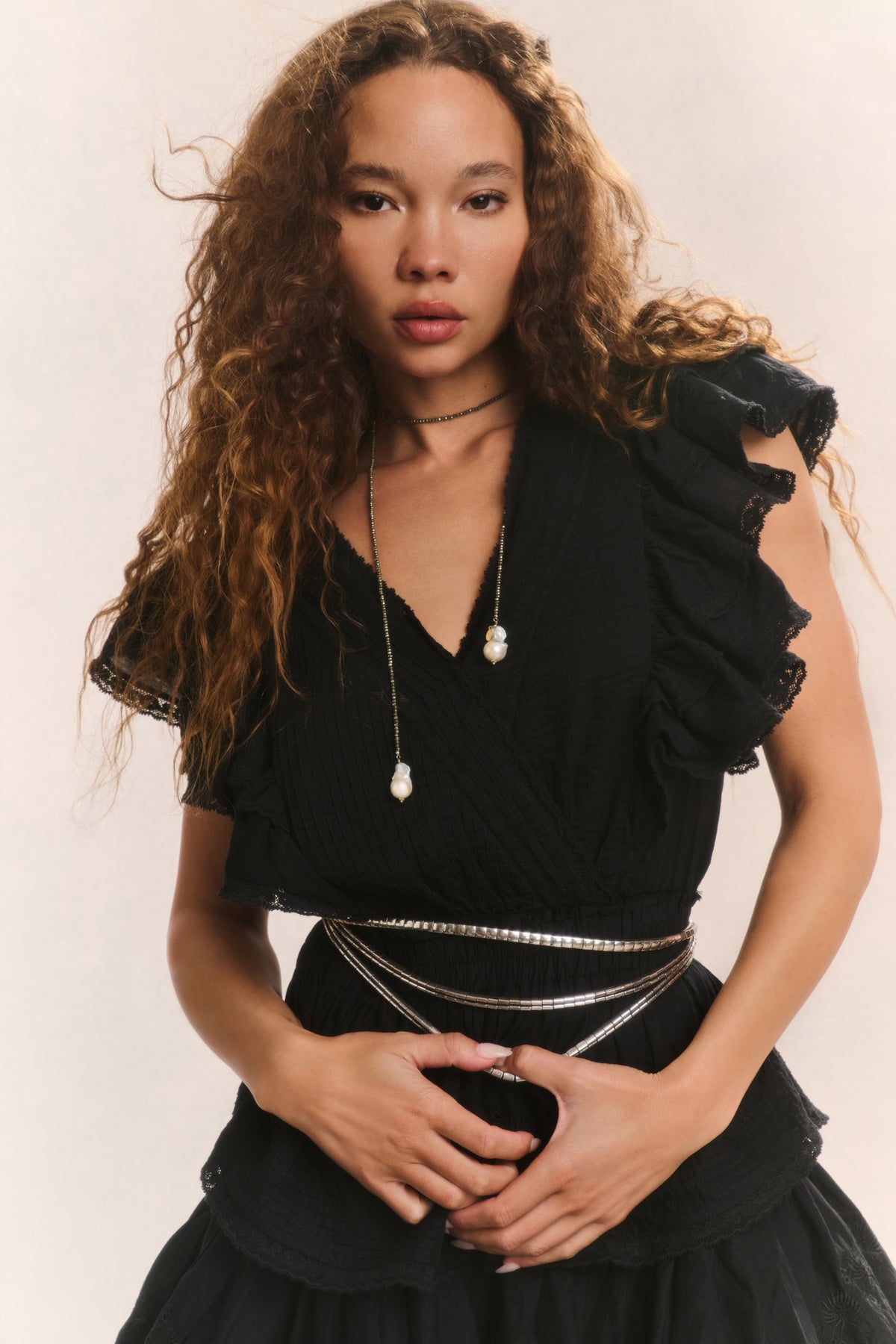 Black V-neck mini dress with ruffled shoulders, tiered skirt, and fitted elastic waist