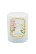 White pillar candle with floral “Harlem” and “Love” label, small flame