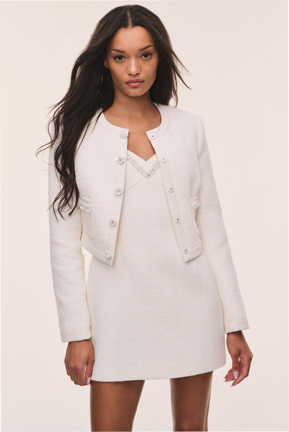 Ivory tweed jacket with button-front, V-neck placket, flap pockets, long sleeves
