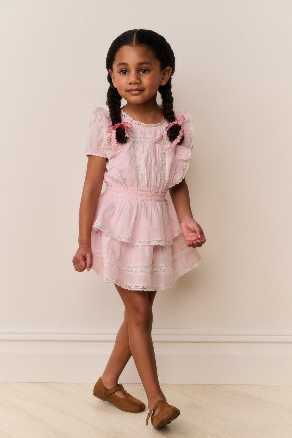 Pink lace-trimmed cotton dress with puff sleeves, tiered skirt, and bows