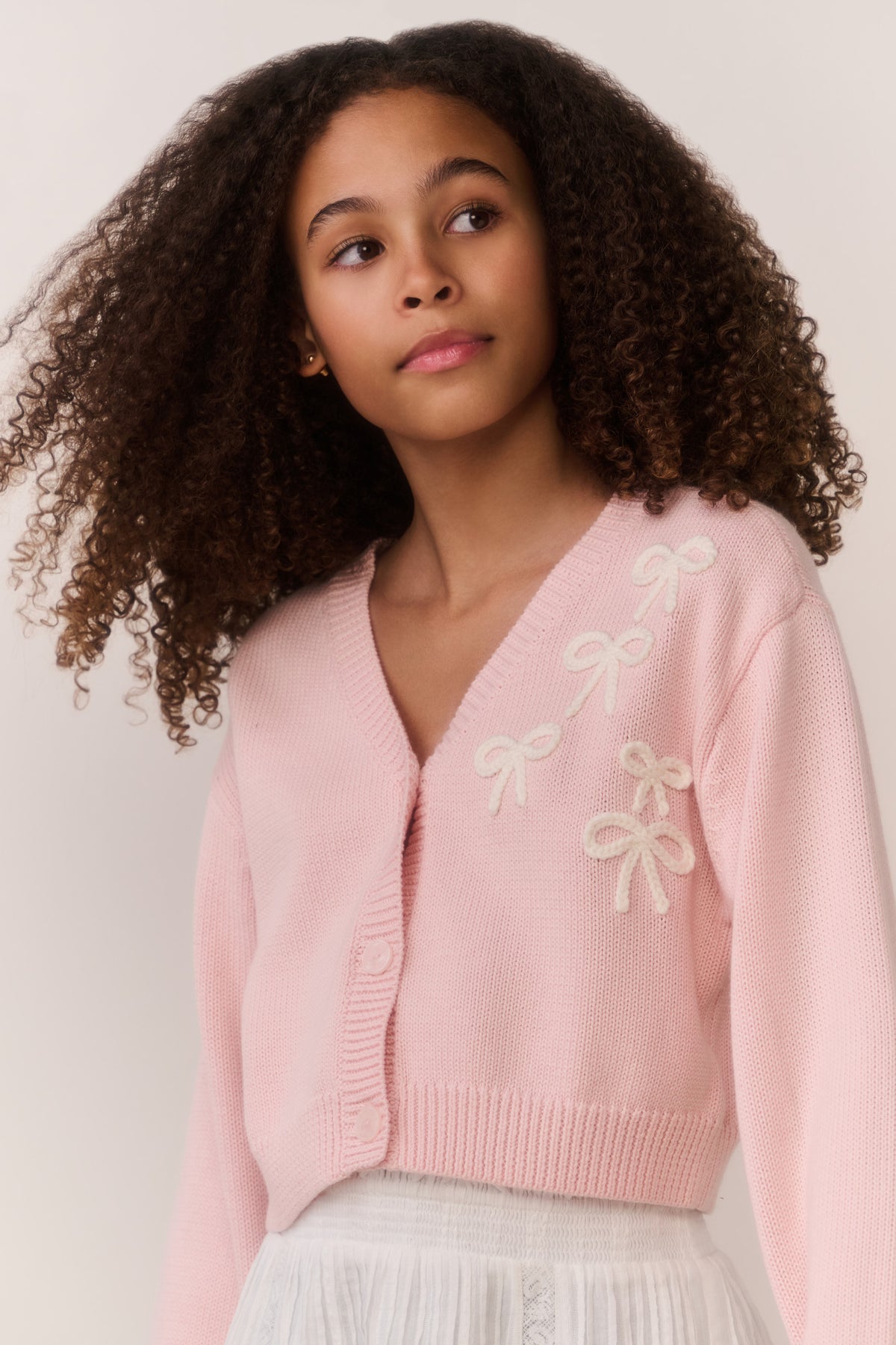Pink cardigan close-up, bow embroidery on shoulder, button-front V-neck, knit texture