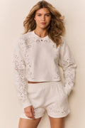 White fleece pullover with long sleeves and scattered eyelet floral cutouts