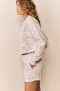 White fleece pullover with eyelet floral cutout embroidery along sleeves
