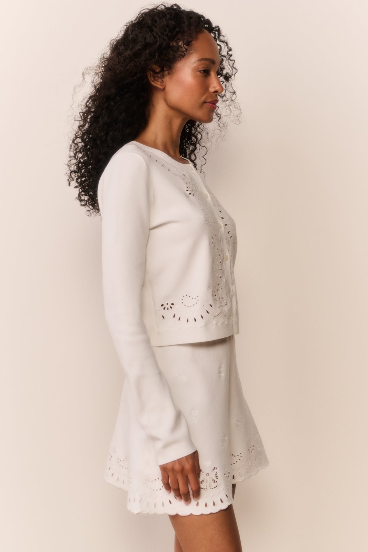 White eyelet knit cardigan side view with button placket and eyelet embroidery.