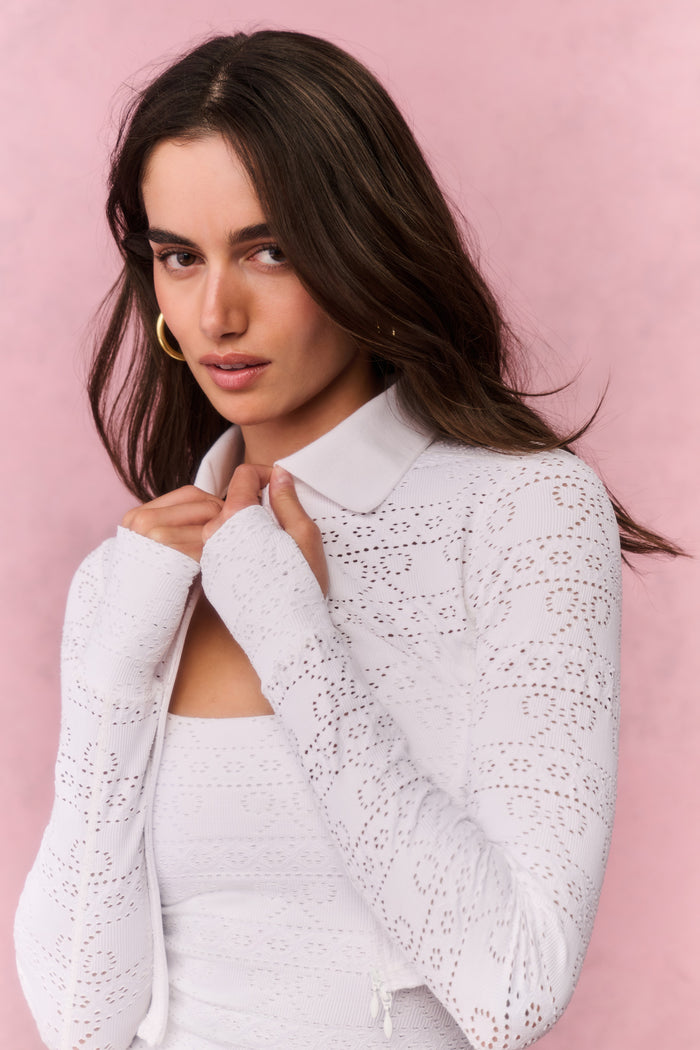 White eyelet active jacket with zip front, raised collar, and long sleeve detail