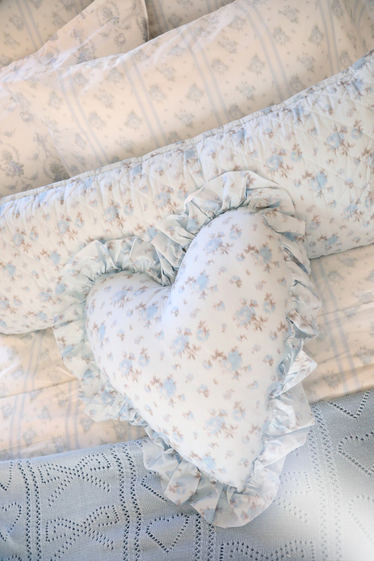 Light blue pointelle throw with gathered ruffle trim and floral cushion detail