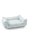 Printed dog bed with light blue floral fabric and low bolstered sides
