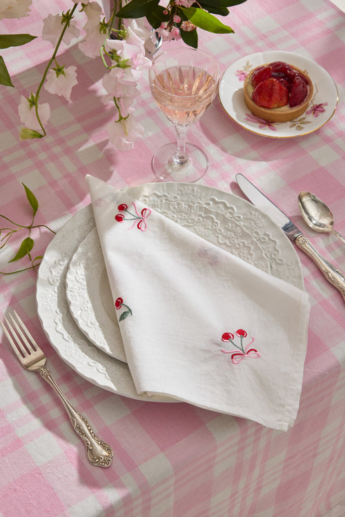 White embroidered napkin with red floral bow and scalloped lace edge