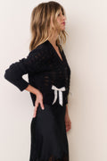 Midnight black bow cardigan with long sleeves, button front, and white ribbon applique