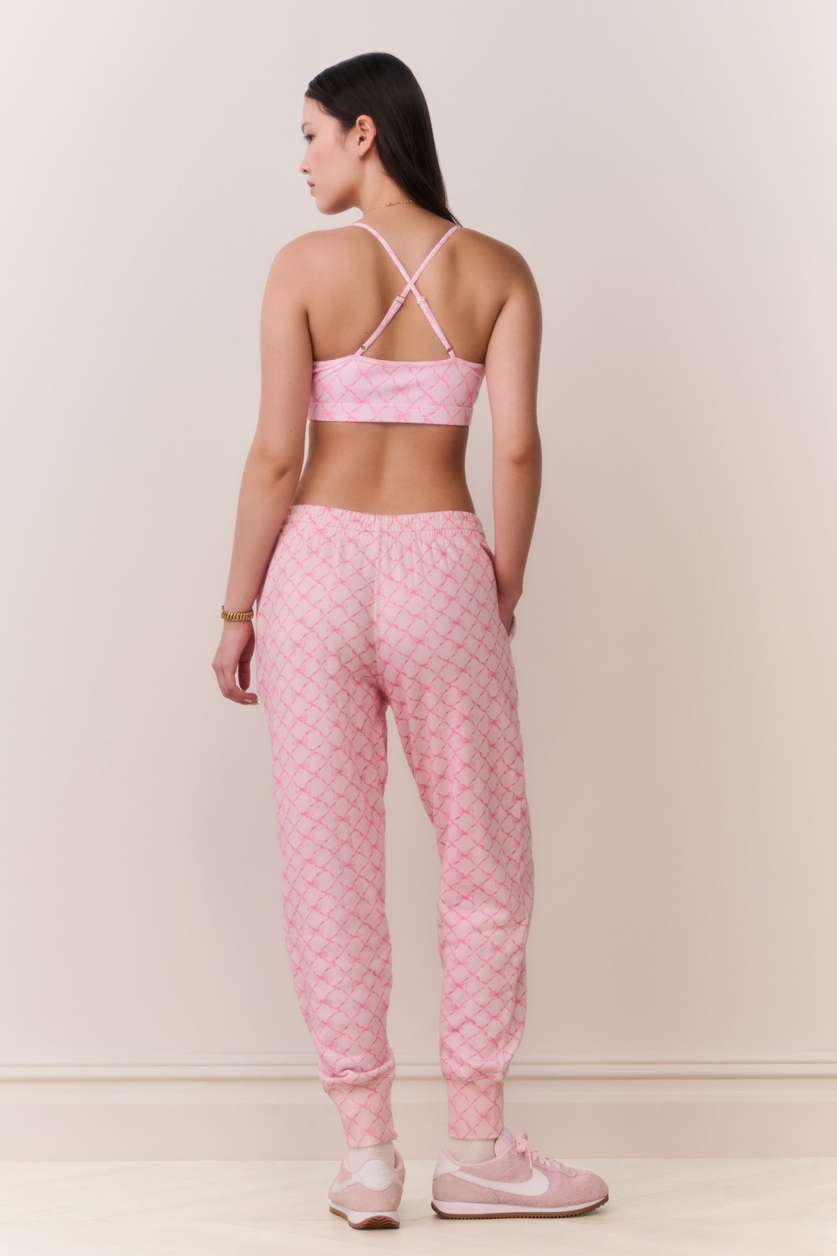 Pink printed cotton sweatpants, back view, elastic cuffs and relaxed tapered legs