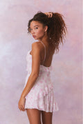 Silk mini dress with open back, thin spaghetti straps, and pink floral print ruffles.