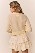 Tiered ruffle mini skirt in pale yellow floral print, worn under sweater