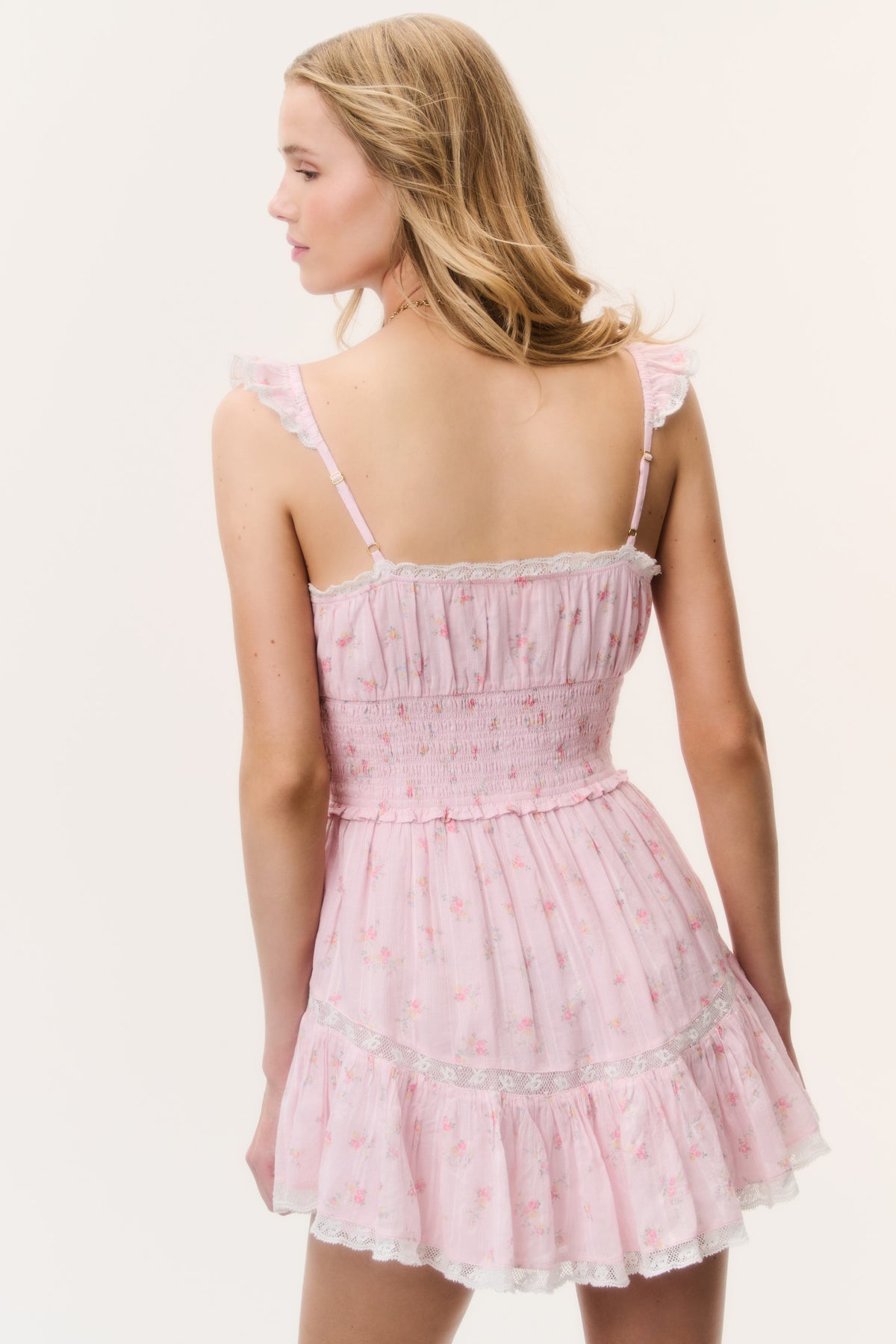 Pink floral cotton mini dress viewed from side, with ruffle-trim straps