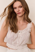 White eyelet crop top close-up with scalloped lace neckline and button placket