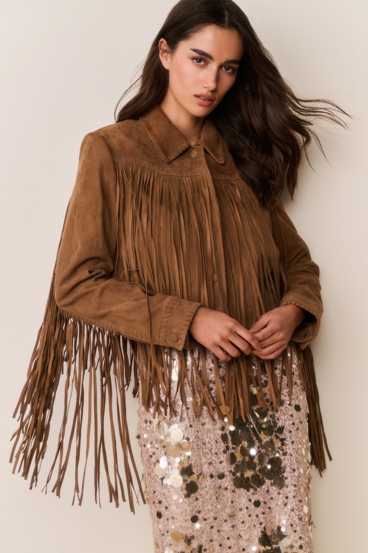 Tan suede fringe jacket with fringed yoke and sleeve tassels over a sequin dress.