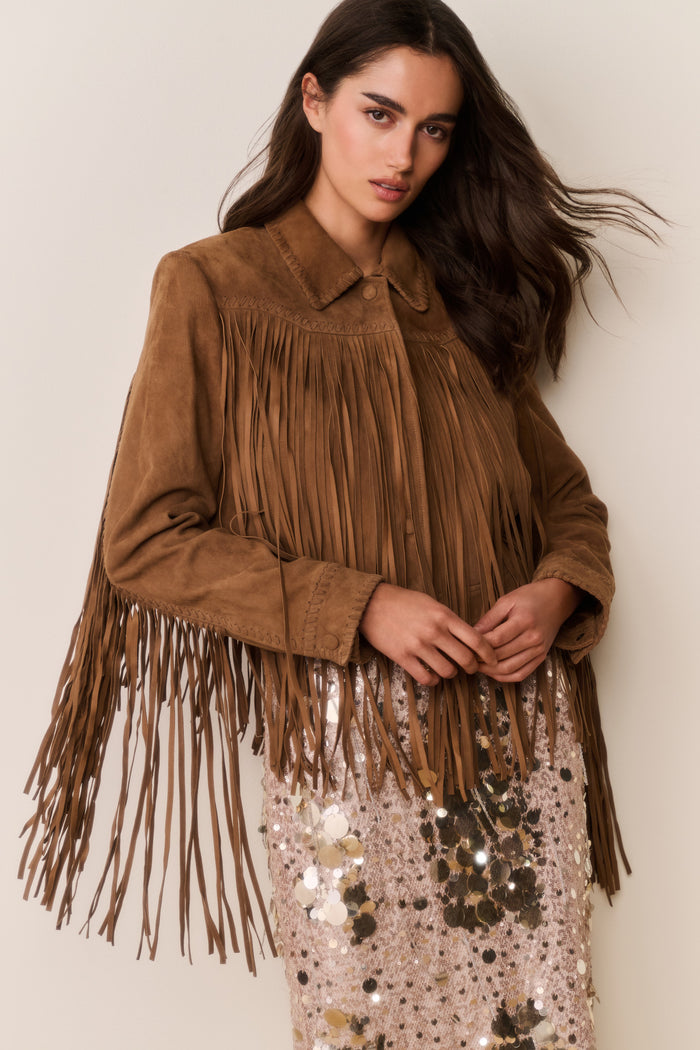 Tan suede fringe jacket with fringed yoke and sleeve tassels over a sequin dress.