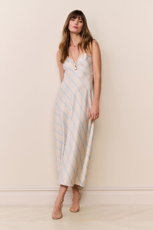Woman wearing a beige and blue striped dress against a plain background