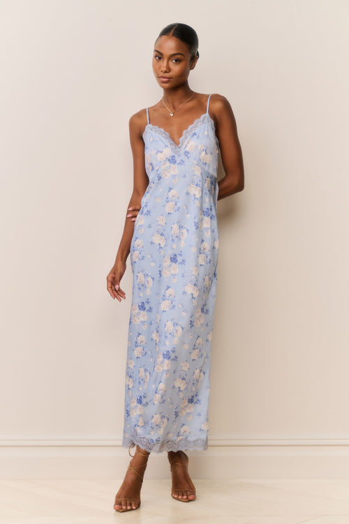 Woman wearing a light blue floral dress against a plain background