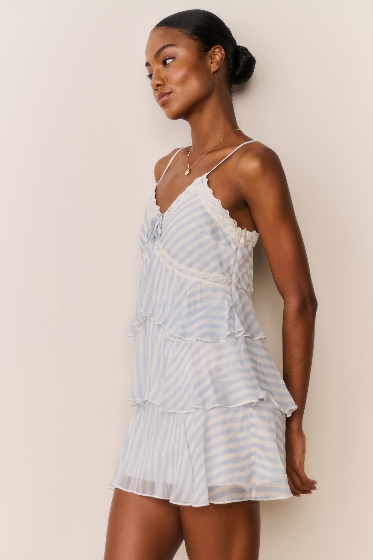 Light blue striped chiffon mini dress from side view, lace trim spaghetti straps, ruffle layers