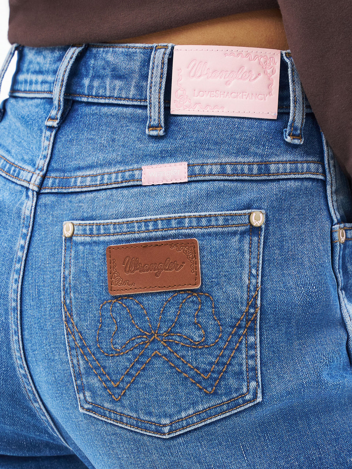 Medium wash cowboy cut jeans with leather logo patch and embroidered back pocket