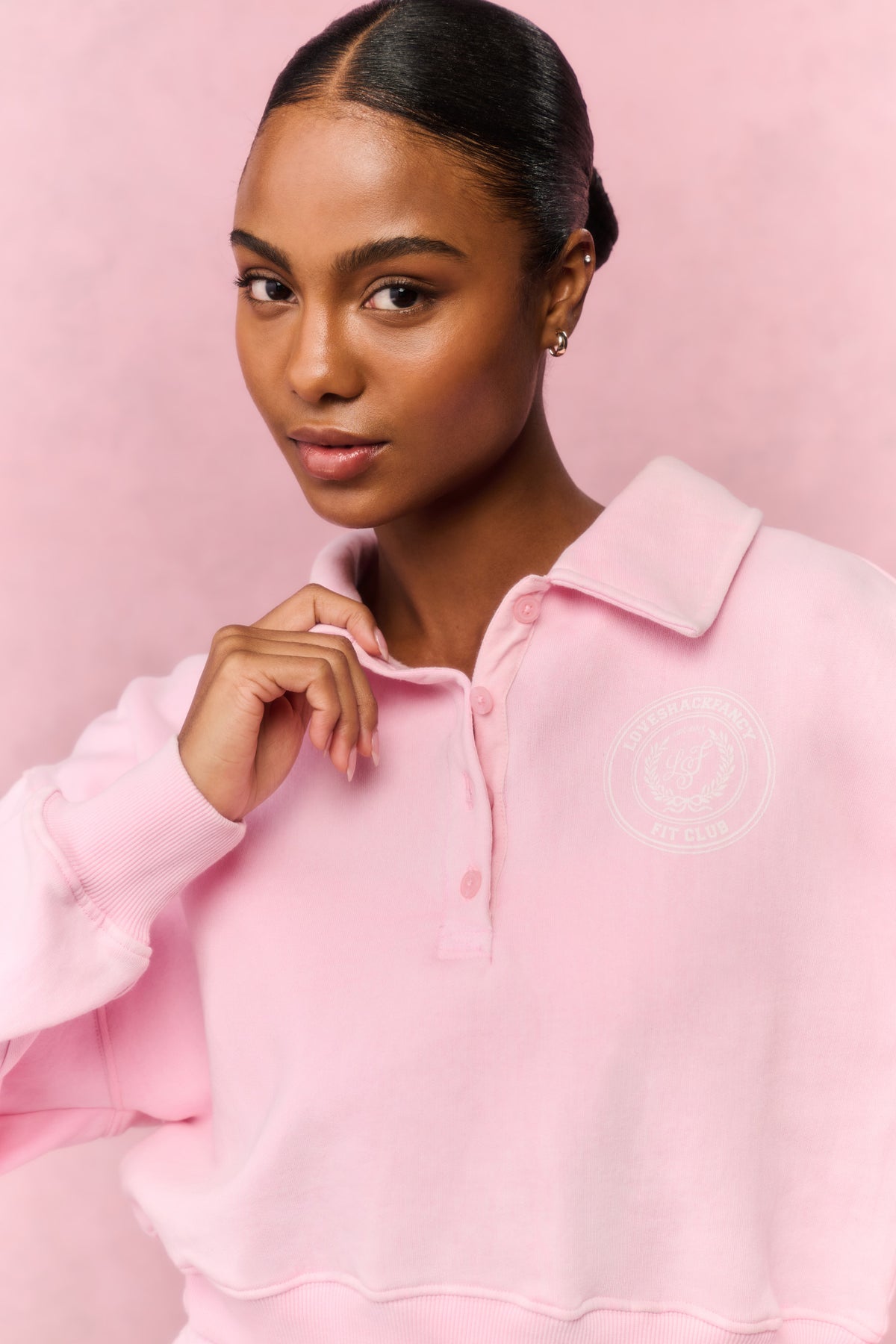 Pink fleece polo sweatshirt with stand collar, button front, and embroidered chest logo