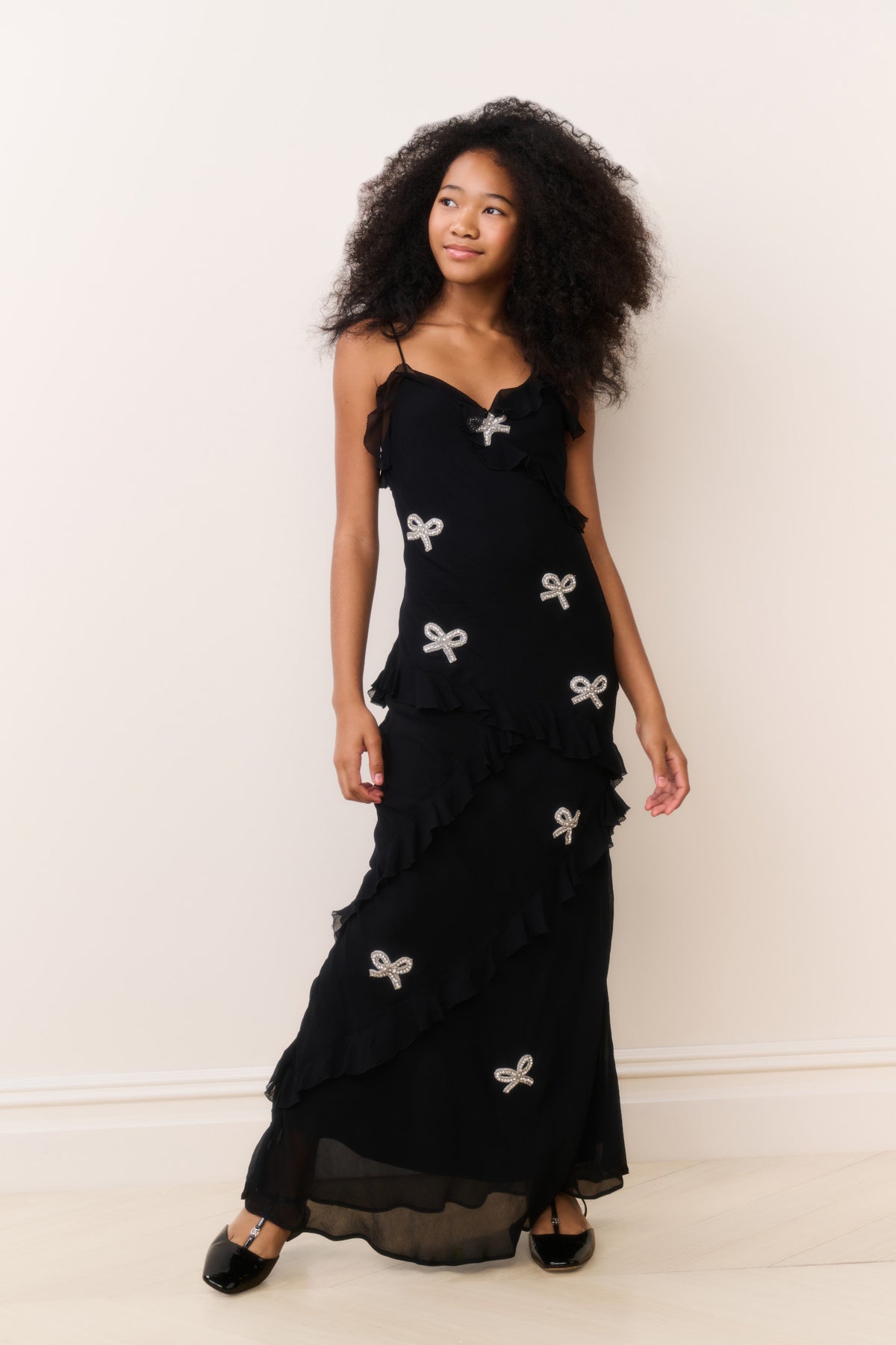 Black sleeveless mini dress with layered ruffles and bow appliques